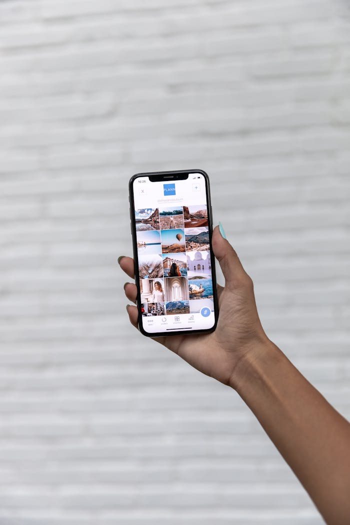 A hand holding a smartphone displaying travel photos against a white textured background.